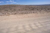 the desert on the side of a road with sparse brown terrain behind it and mountains in the distance