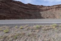 a person riding a motorcycle along a narrow road through rocks and sand cliffs a grassy area on both sides