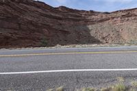 a person riding a motorcycle along a narrow road through rocks and sand cliffs a grassy area on both sides