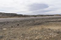 a sign warning of an approaching vehicle on the highway through rocky terrain in a dry, barren area