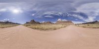 a view through a google - friendly image of a dirt road in the desert, with large mountains and sparse grass surrounding