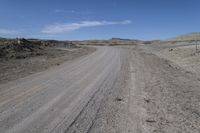 a dirt road is surrounded by some hills and desert like terrain as the vehicle sits on it