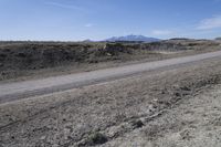 a dirt road is surrounded by some hills and desert like terrain as the vehicle sits on it