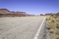 a desert road with rocky terrain and blue sky in the background on a sunny day