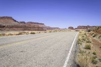 a desert road with rocky terrain and blue sky in the background on a sunny day