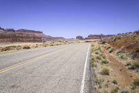 a desert road with rocky terrain and blue sky in the background on a sunny day