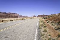 a desert road with rocky terrain and blue sky in the background on a sunny day