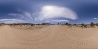 a panorama mirror view of a desert and some bushes on the side of a dirt road