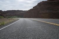 a person riding a motorcycle along a narrow road through rocks and sand cliffs a grassy area on both sides