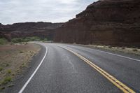 a person riding a motorcycle along a narrow road through rocks and sand cliffs a grassy area on both sides