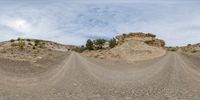 a dirt road passing through the desert like terrain as it passes by another area with grass and shrubbery