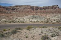 an empty road winds up through a barren landscape to the side of a mountain range