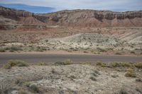 an empty road winds up through a barren landscape to the side of a mountain range