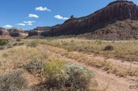 an image of a dirt road in the desert in the day time by some mountains