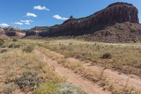 an image of a dirt road in the desert in the day time by some mountains