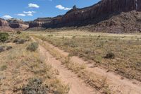 an image of a dirt road in the desert in the day time by some mountains