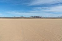 a desert with the desert ground covered in sand and a lone person walking across it