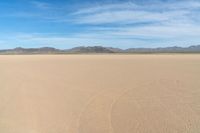 a desert with the desert ground covered in sand and a lone person walking across it