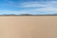 a desert with the desert ground covered in sand and a lone person walking across it