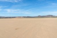 a desert with the desert ground covered in sand and a lone person walking across it