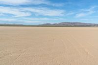 a desert with the desert ground covered in sand and a lone person walking across it