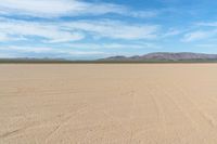 a desert with the desert ground covered in sand and a lone person walking across it