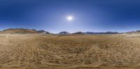 a wide view shows dirt and snow in the desert at twilight or dawn as well as the sun