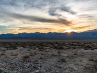 sunset in mountains and desert plains with sun reflecting in window glass of vehicle's