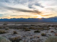 sunset in mountains and desert plains with sun reflecting in window glass of vehicle's