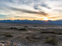 sunset in mountains and desert plains with sun reflecting in window glass of vehicle's