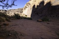 dirt and grass grow in the middle of a gorge between mountains with clear sky above