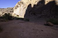 dirt and grass grow in the middle of a gorge between mountains with clear sky above