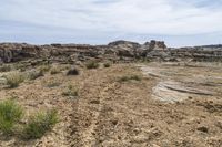 barren, rocky area with sparse grass on the ground and rocks in the background along a mountain