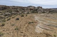 barren, rocky area with sparse grass on the ground and rocks in the background along a mountain