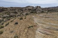 barren, rocky area with sparse grass on the ground and rocks in the background along a mountain