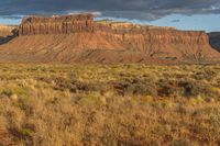 an empty field with rocky terrain near a desert area of brown grass, yellow weeds and brown sky