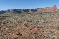 the barren, blue and red landscape of a desert plain with mountains in the background