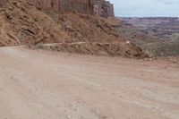 a dirt road with some rocks on both sides and dirt running on each side with steep cliffs at the bottom and bottom