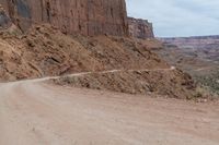 a dirt road with some rocks on both sides and dirt running on each side with steep cliffs at the bottom and bottom