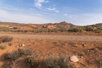 a large sandy field surrounded by trees and dirt hills and shrubss in the desert