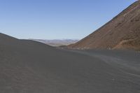 a motorcycle is parked in the middle of a barren desert valley in the foreground is a mountain range