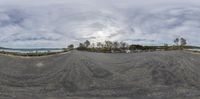 a fish eye view of a deserted asphalt roadway in the country side under cloudy skies