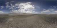 a wide view of an empty beach with low clouds in the sky and there is a man that can be seen