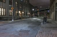 the bricked sidewalk by the building is deserted at night with no lights on it