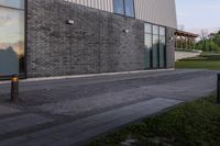 an open fire hydrant sits next to an empty building outside a glass windowed area