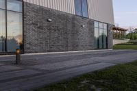 an open fire hydrant sits next to an empty building outside a glass windowed area