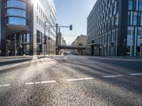 sunlight shines brightly on a deserted city street with buildings and pedestrians on the road