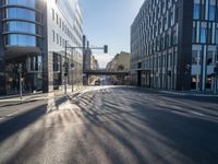 sunlight shines brightly on a deserted city street with buildings and pedestrians on the road