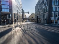 sunlight shines brightly on a deserted city street with buildings and pedestrians on the road