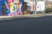 the street is deserted in this city with colorful graffiti walls on the building side and street art